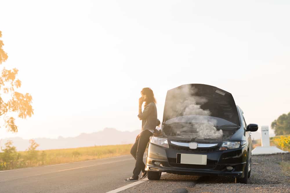 Broken car. Lady standing on the road